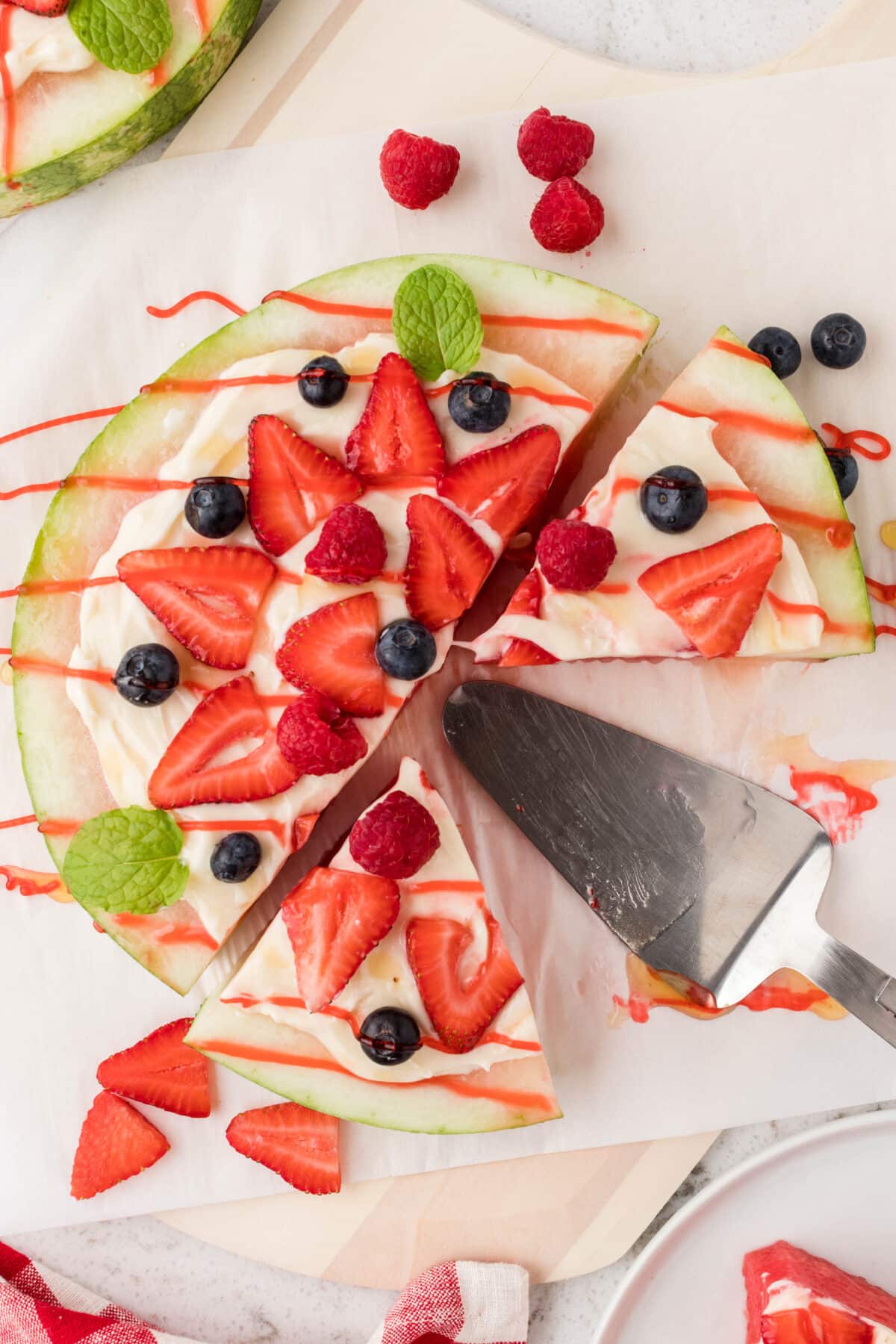 A slice of watermelon topped with fluffy icing, fresh strawberries, and cut into slices.