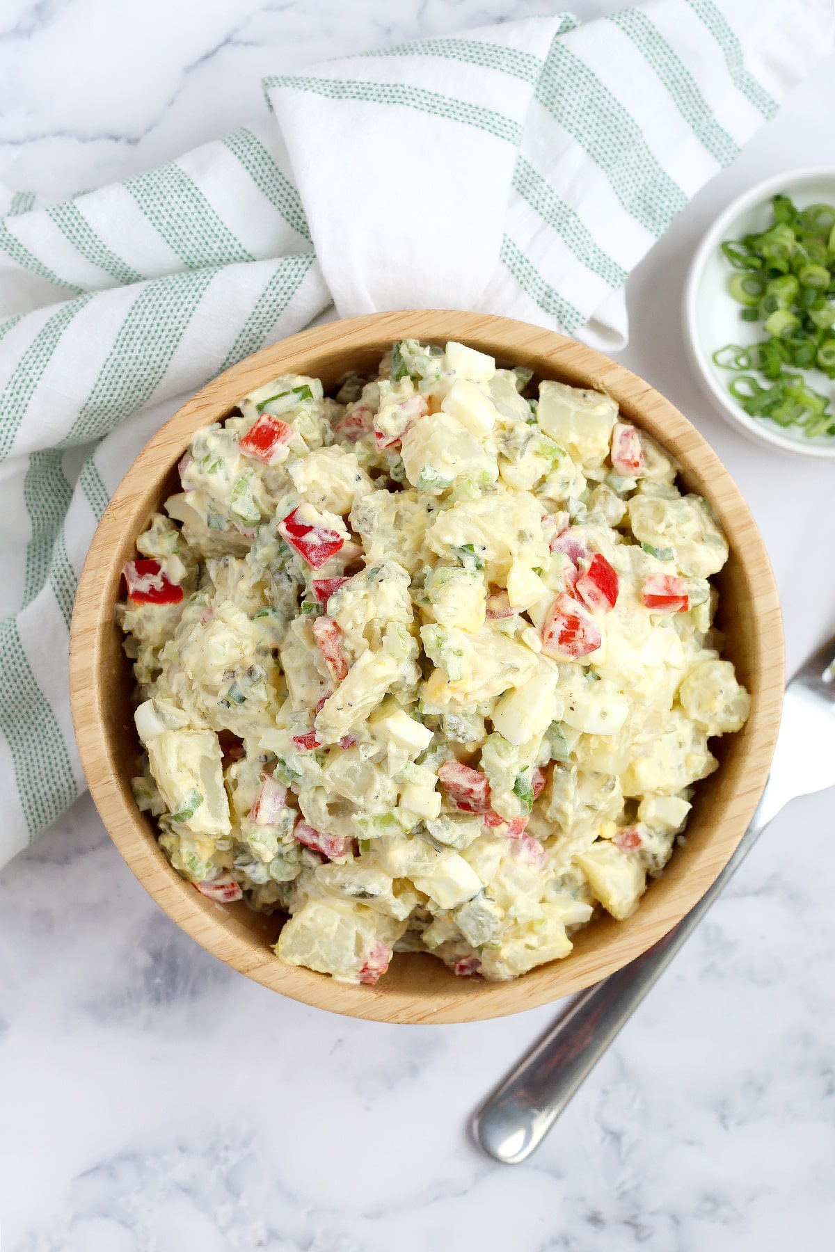 A bowl of potato salad with a white and green striped linen.