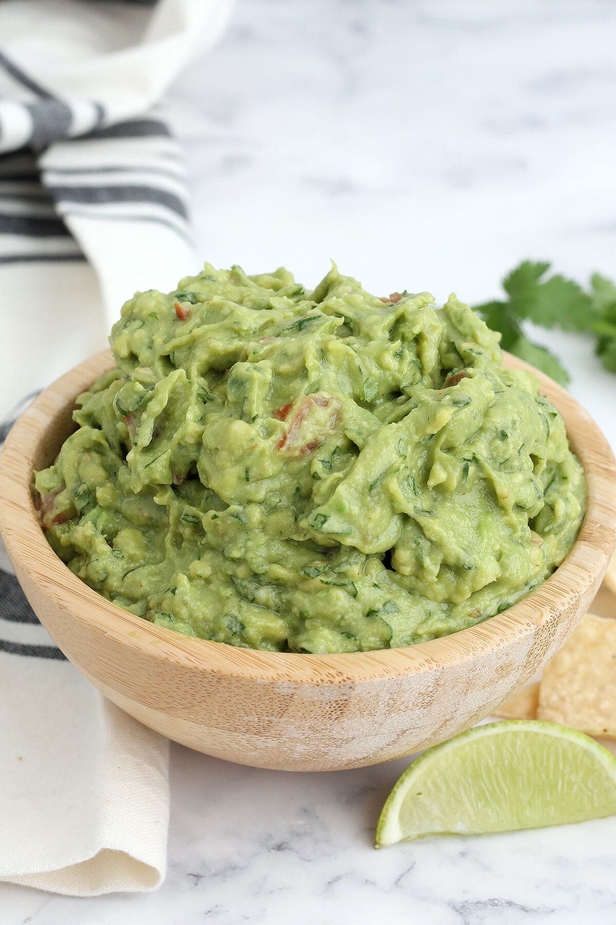 fresh guacamole with tomatoes in a wooden bowl