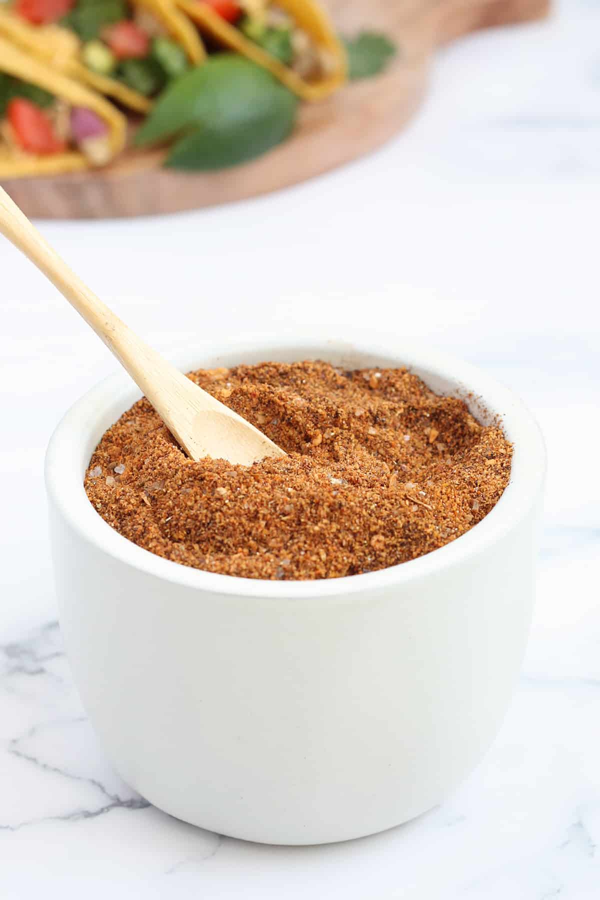 A white ceramic jar filled with homemade taco seasoning