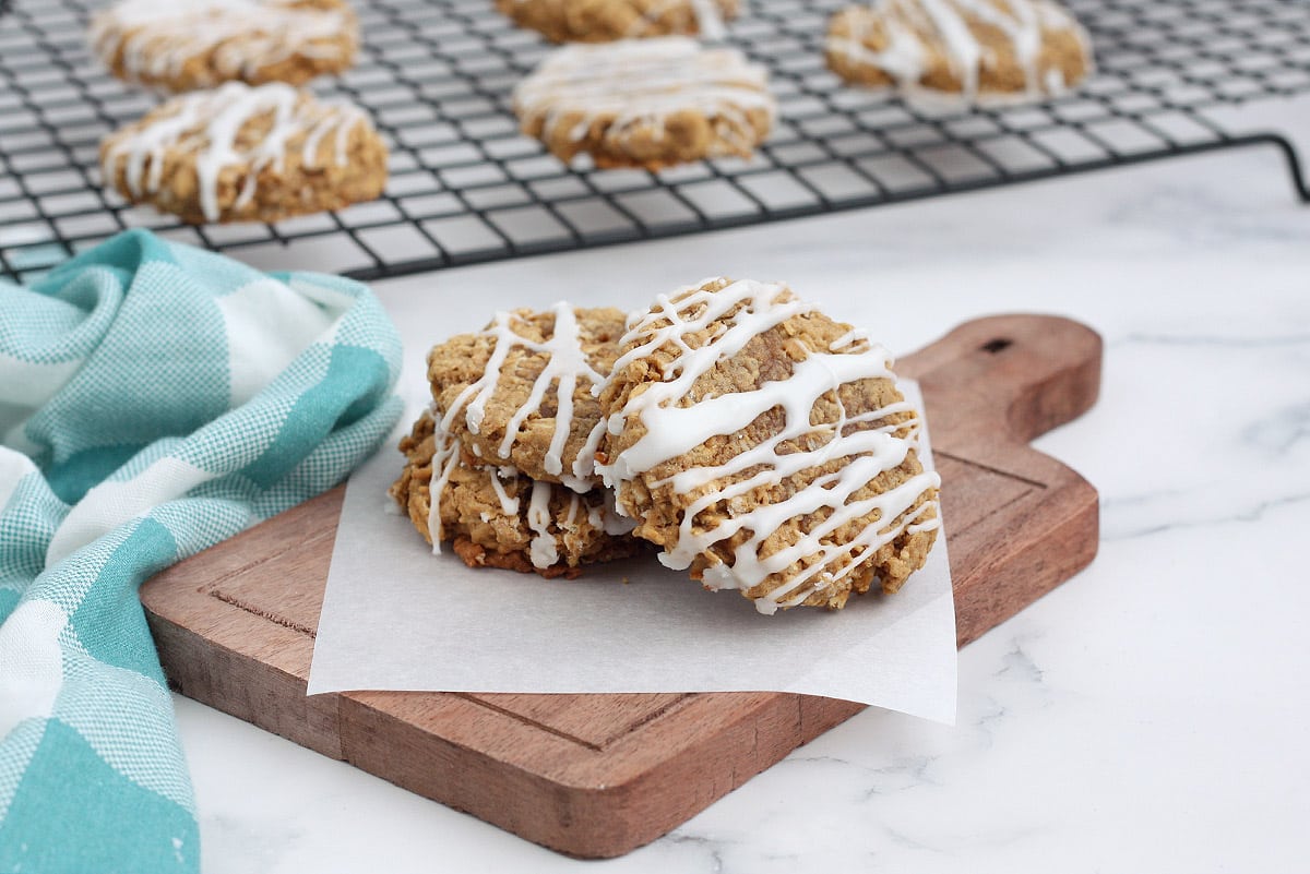 iced oatmeal cookies on a wooden cutting board