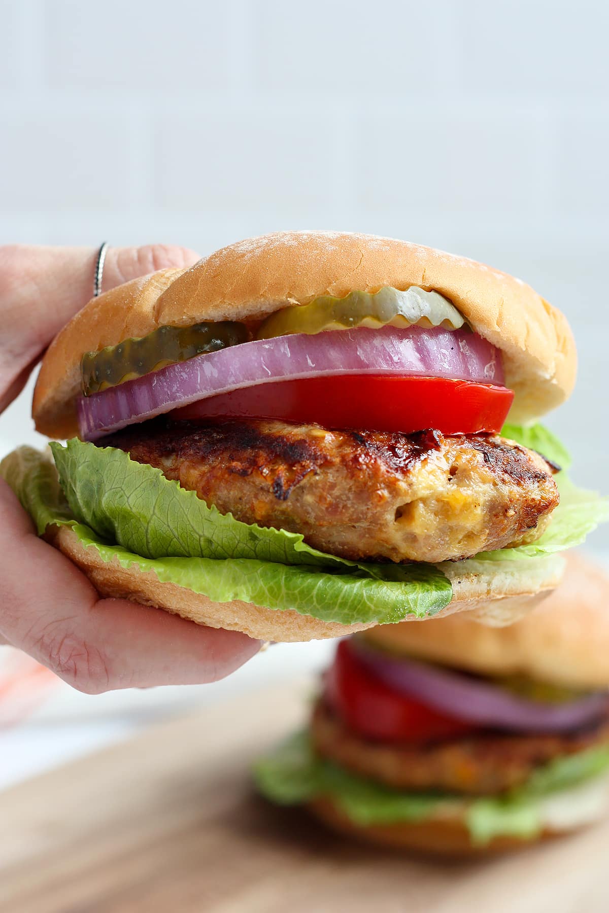 A closeup image of a turkey burger on a white bun with toppings.