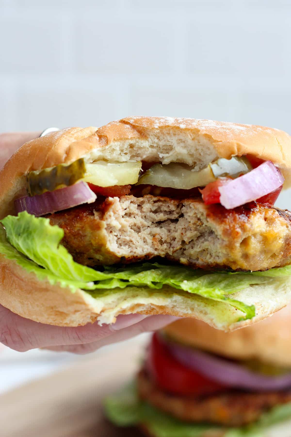 A juicy turkey burger with something bitten out of.
