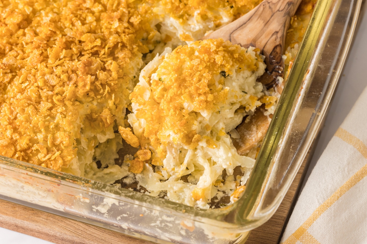 A glass casserole dish with cheesy potatoes topped with crushed cornflakes.