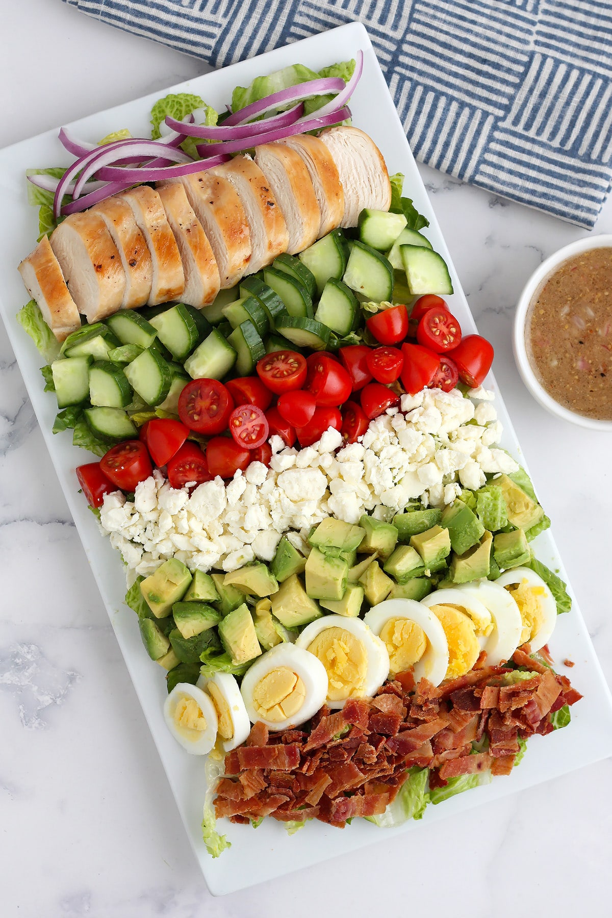 Layered cobb salad recipe on a white serving platter.