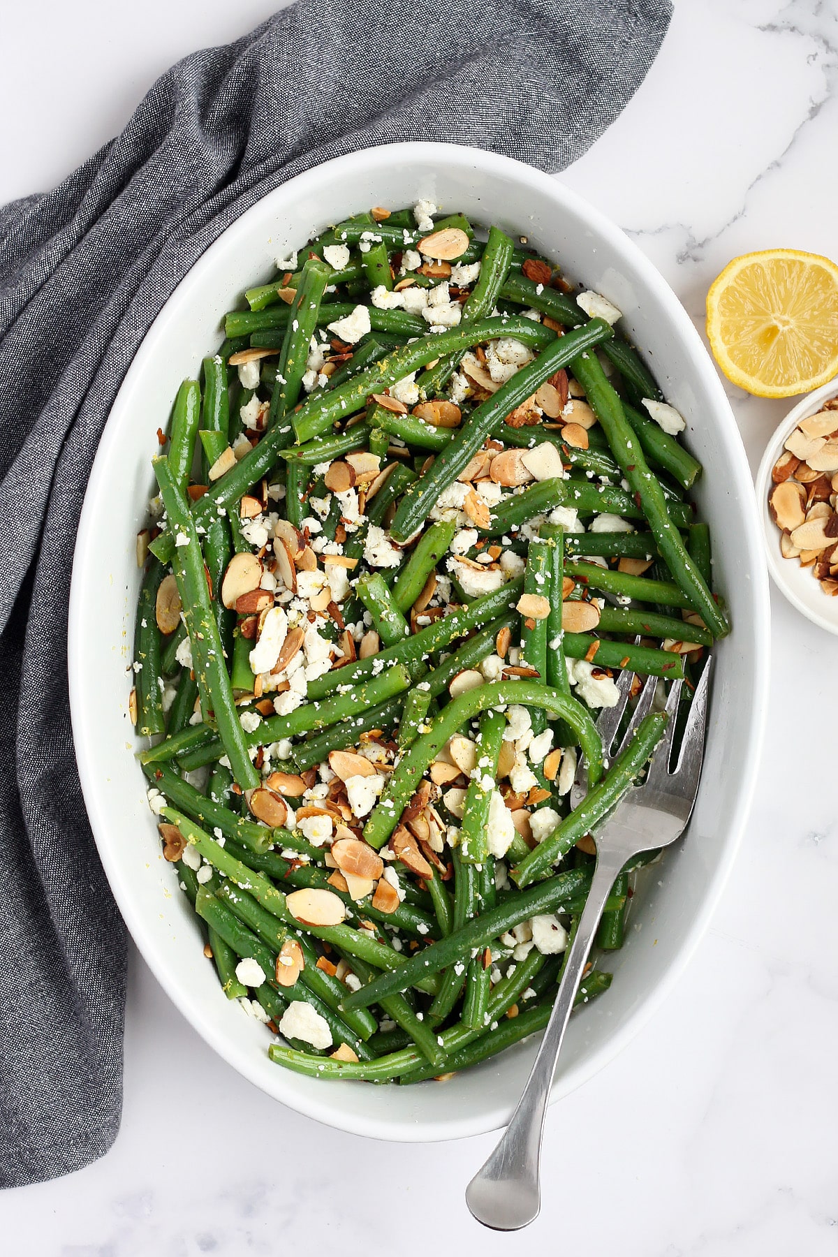 A shot of green beans topped with toasted almonds and feta cheese.