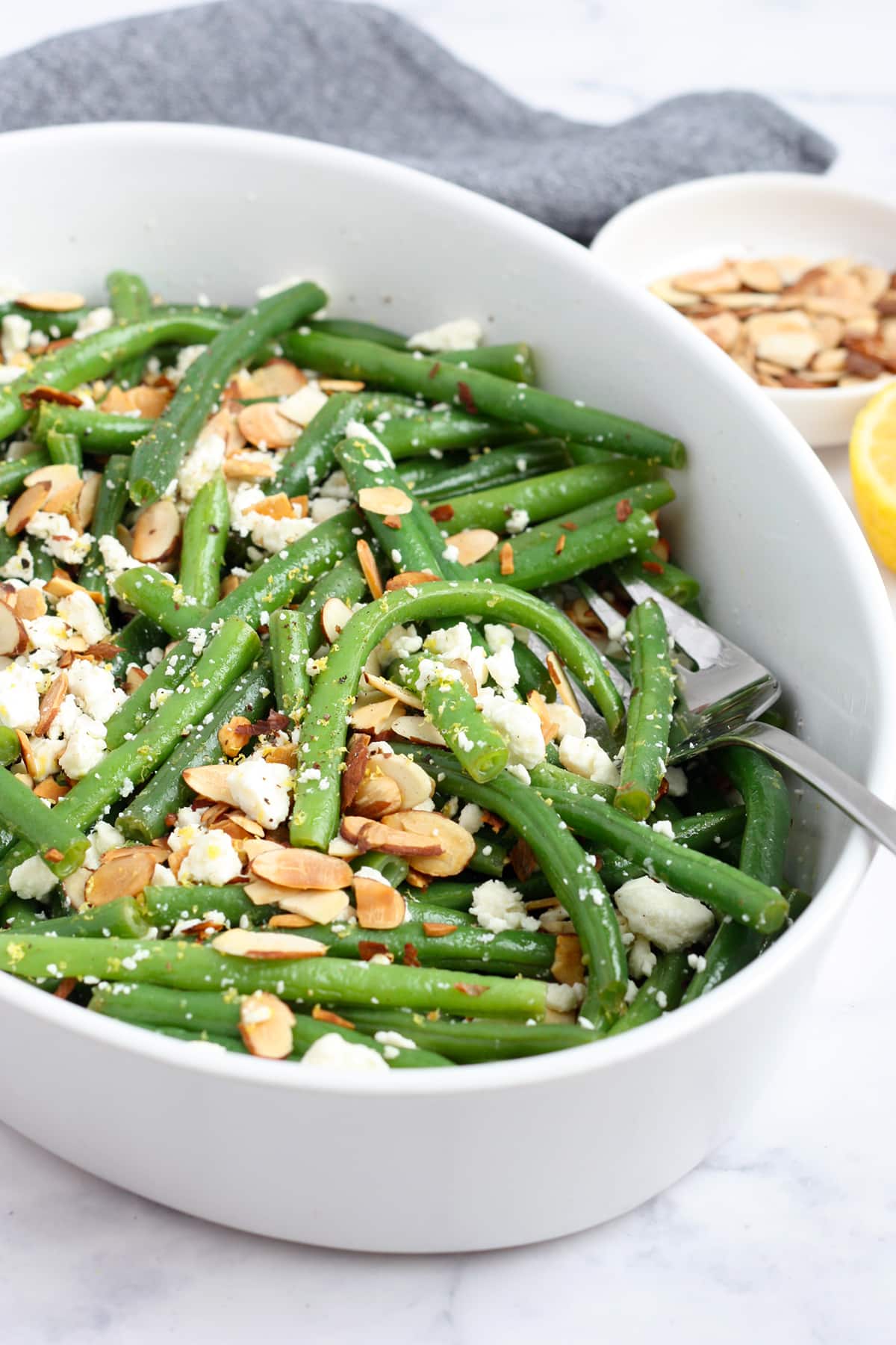 A plate of fresh green beans tossed with a lemon vinaigrette sauce.