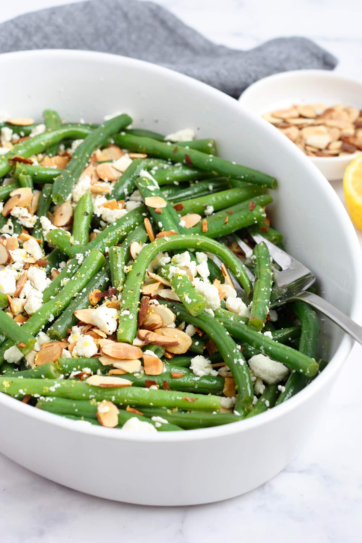 Fresh green bean tossed in a lemon vinaigrette in a serving dish.