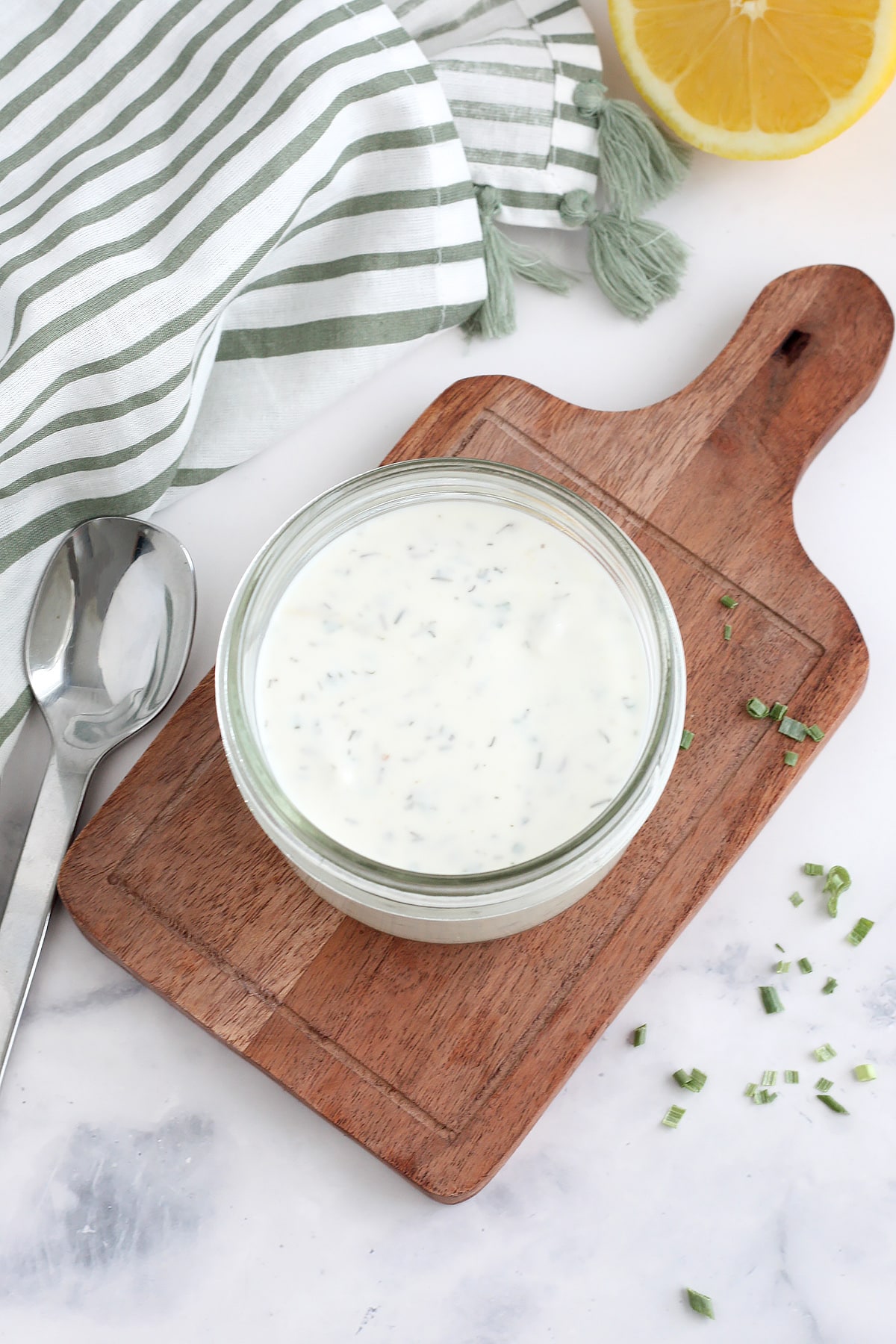 Creamy 5 minute homemade ranch - perfect for a crunchy veggie tray! 4 A jar of homemade ranch dressing on a small wooden board with a scattering of dried chives.