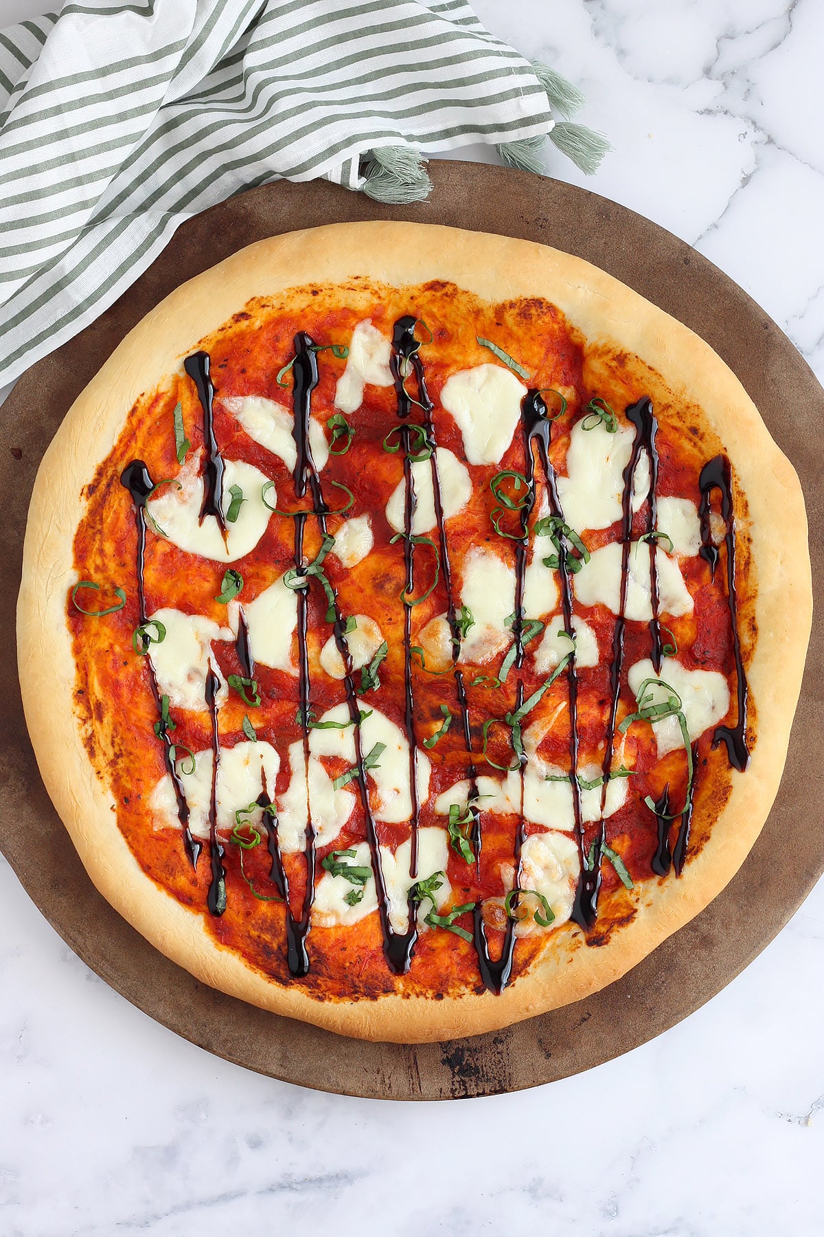 A homemade margherita pizza topped with fresh mozzarella, basil, and balsamic drizzle.