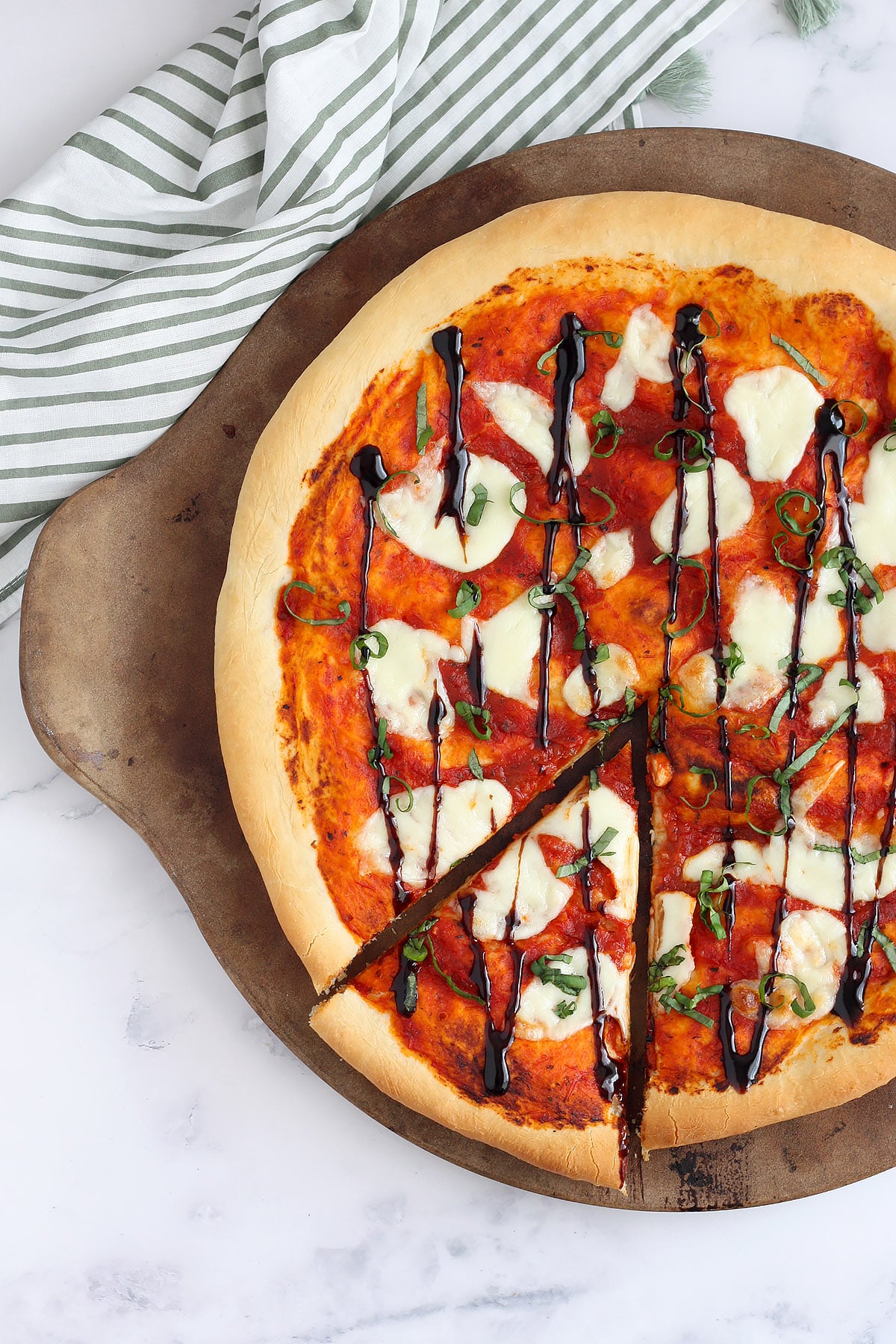 Homemade margherita pizza topped with fresh basil and a balsamic drizzle.