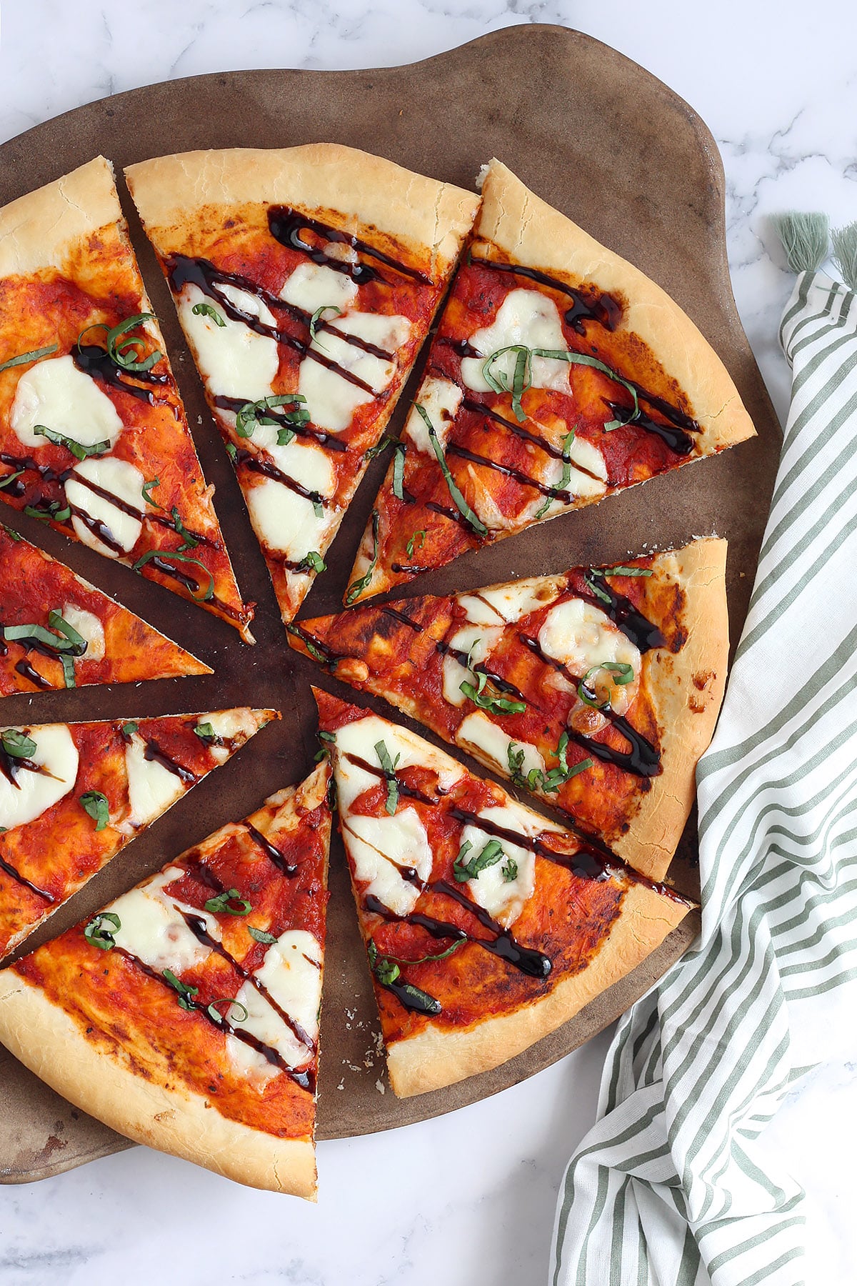 A recipe for Margherita pizza sliced ​​on a ceramic pizza stone.