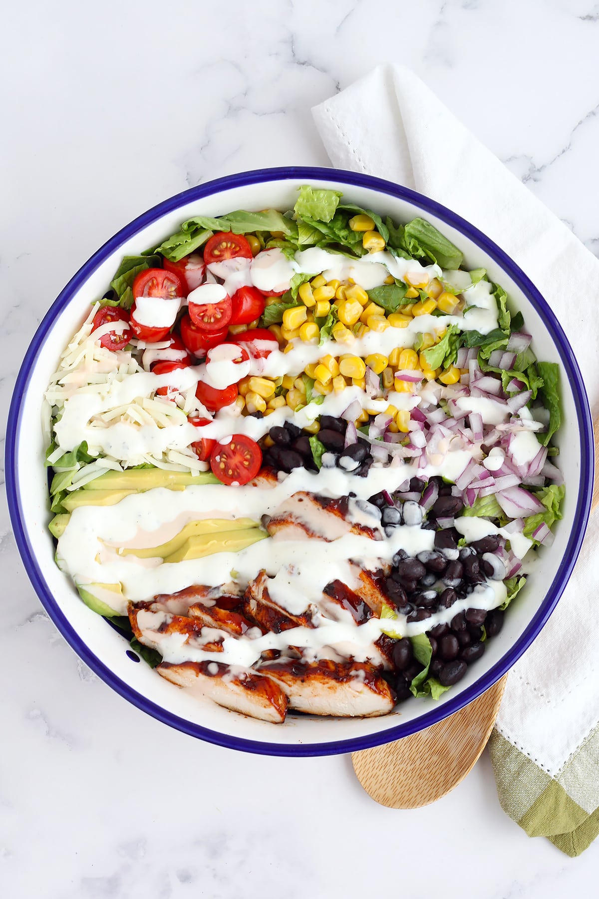 A refreshing grilled chicken salad with fresh vegetables, chicken and mozzarella cheese, drizzled with ranch dressing.