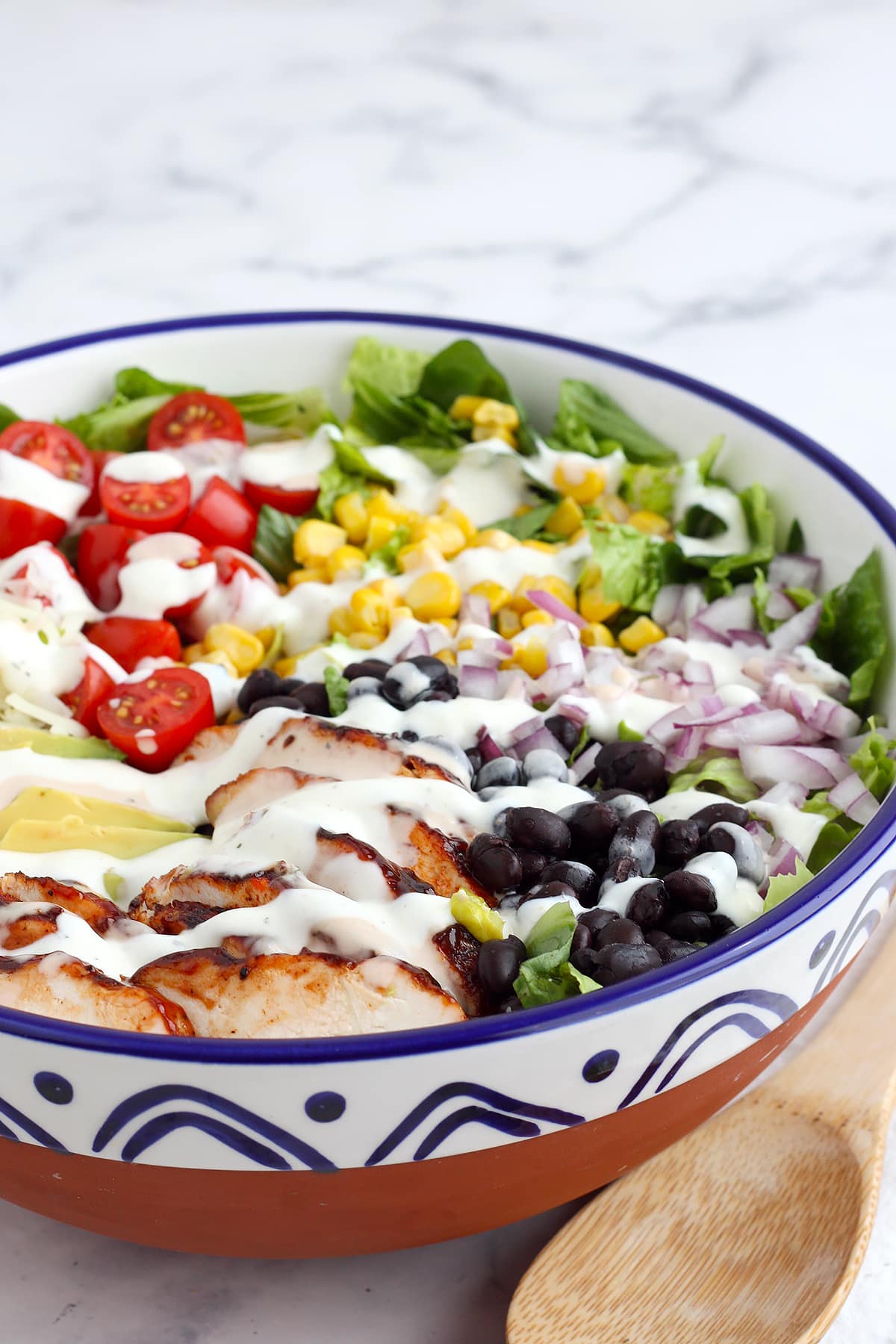 Chicken Salad topped with fresh corn, black beans, tomatoes and avocado drizzled with a bbq ranch dressing.