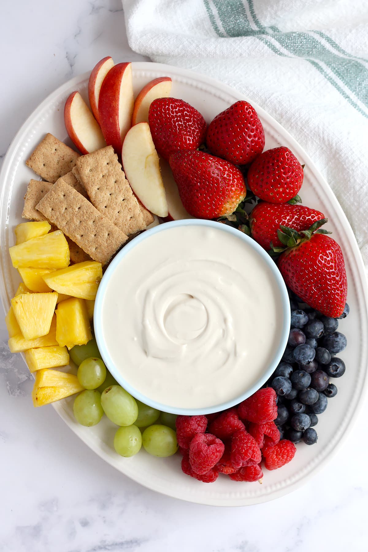 A large white platter with fresh fruit and cream cheese fruit dip.