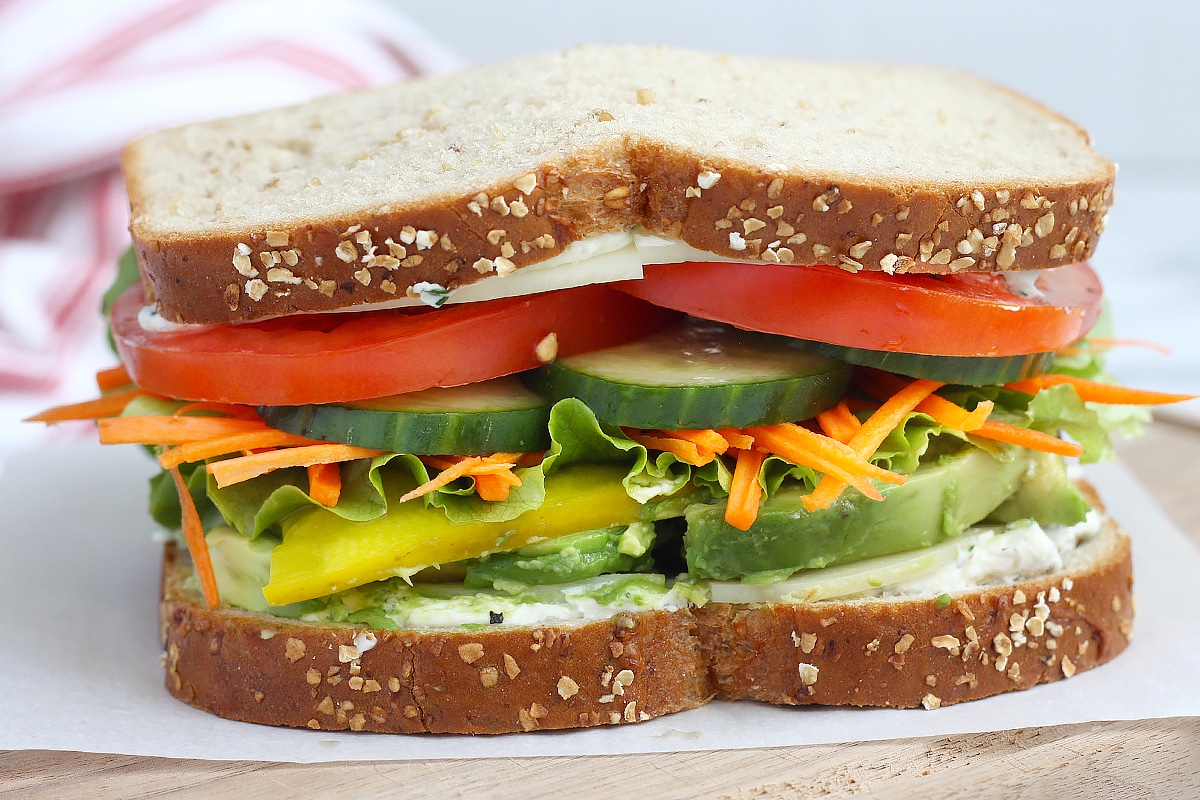 A close up picture of a vegetable sandwich with a striped linen in the background.