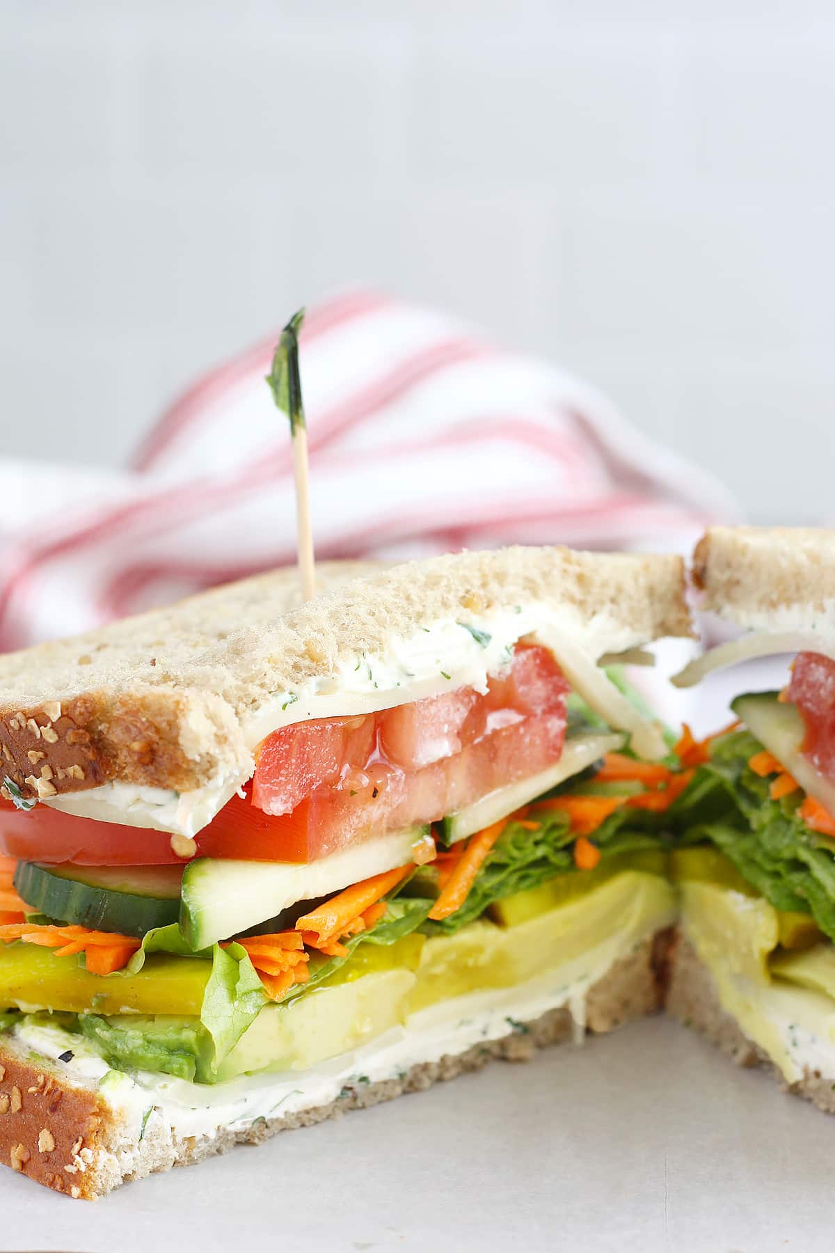 A loaded veggie sandwich with herbed cream cheese on wheat bread.