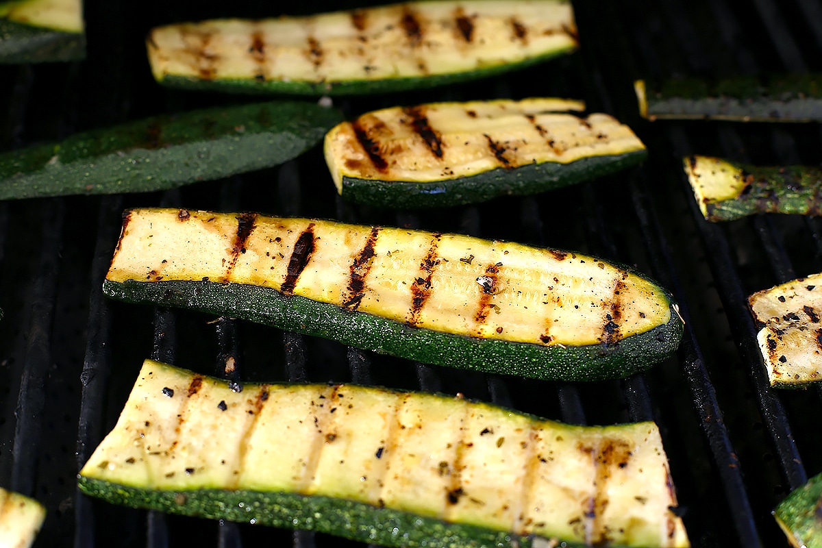 Thick slices of marinated zucchini on a grill.