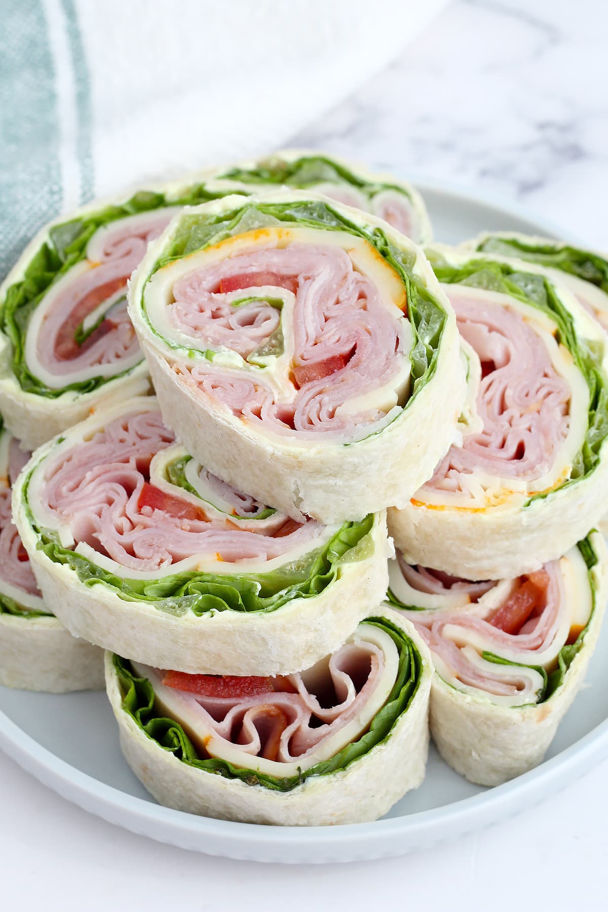 Ham and cheese pinwheels stacked on a plate.