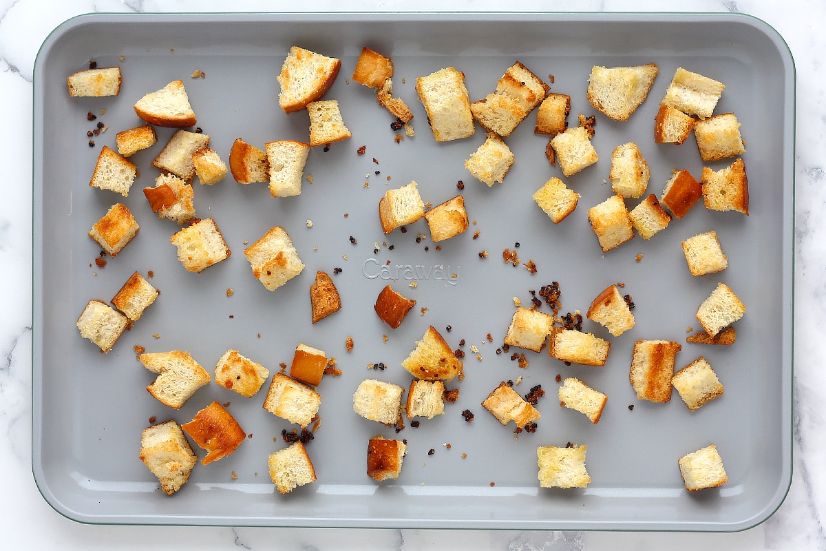 Homemade croutons made with french bread on a baking sheet.
