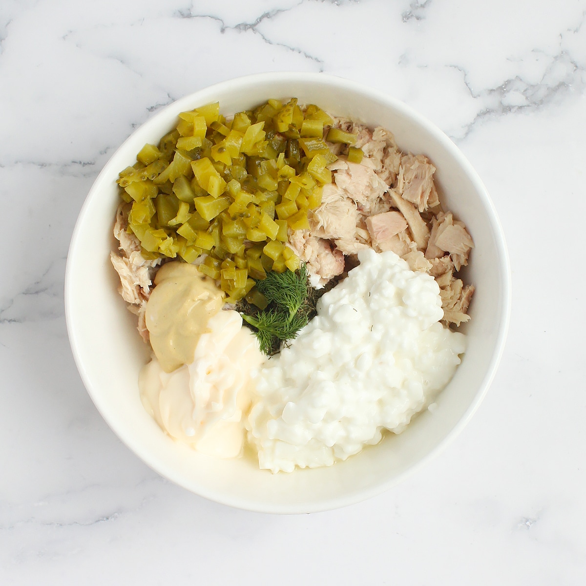 Tuna salad ingredients in a white bowl.