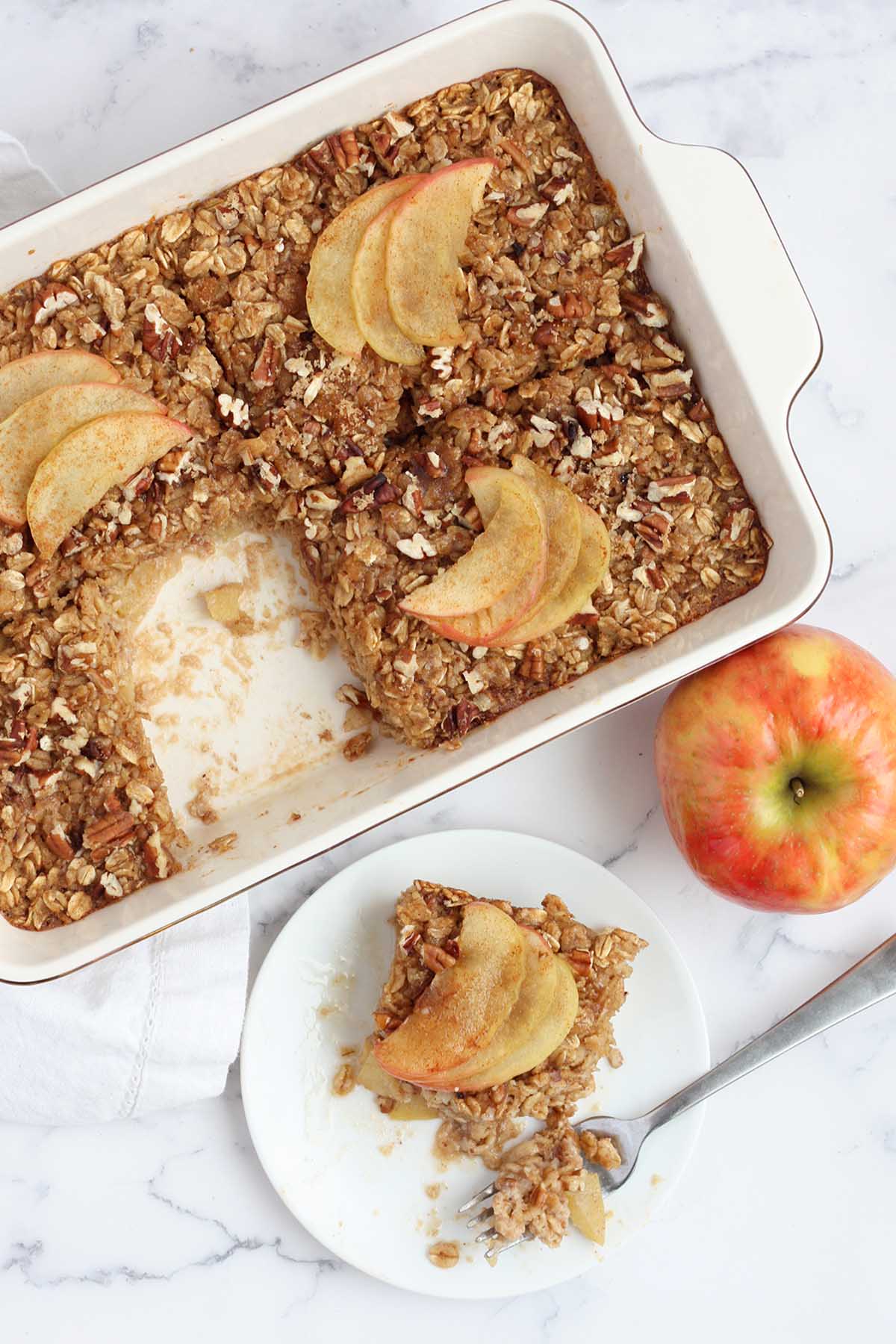 An overhead shot of a pan of baked oatmeal topped with sliced apples.