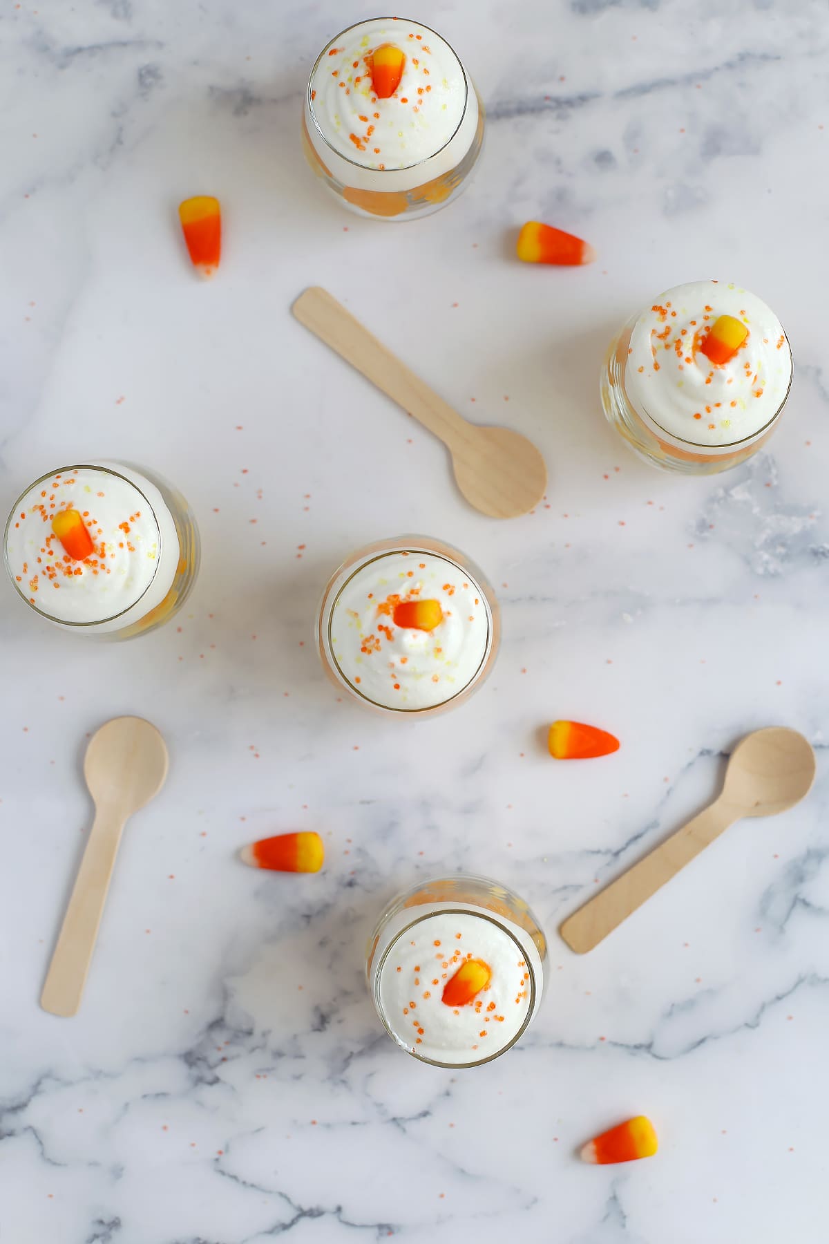 Little candy corn parfaits topped with whipped cottage cheese, orange and yellow sprinkles, and a candy corn.