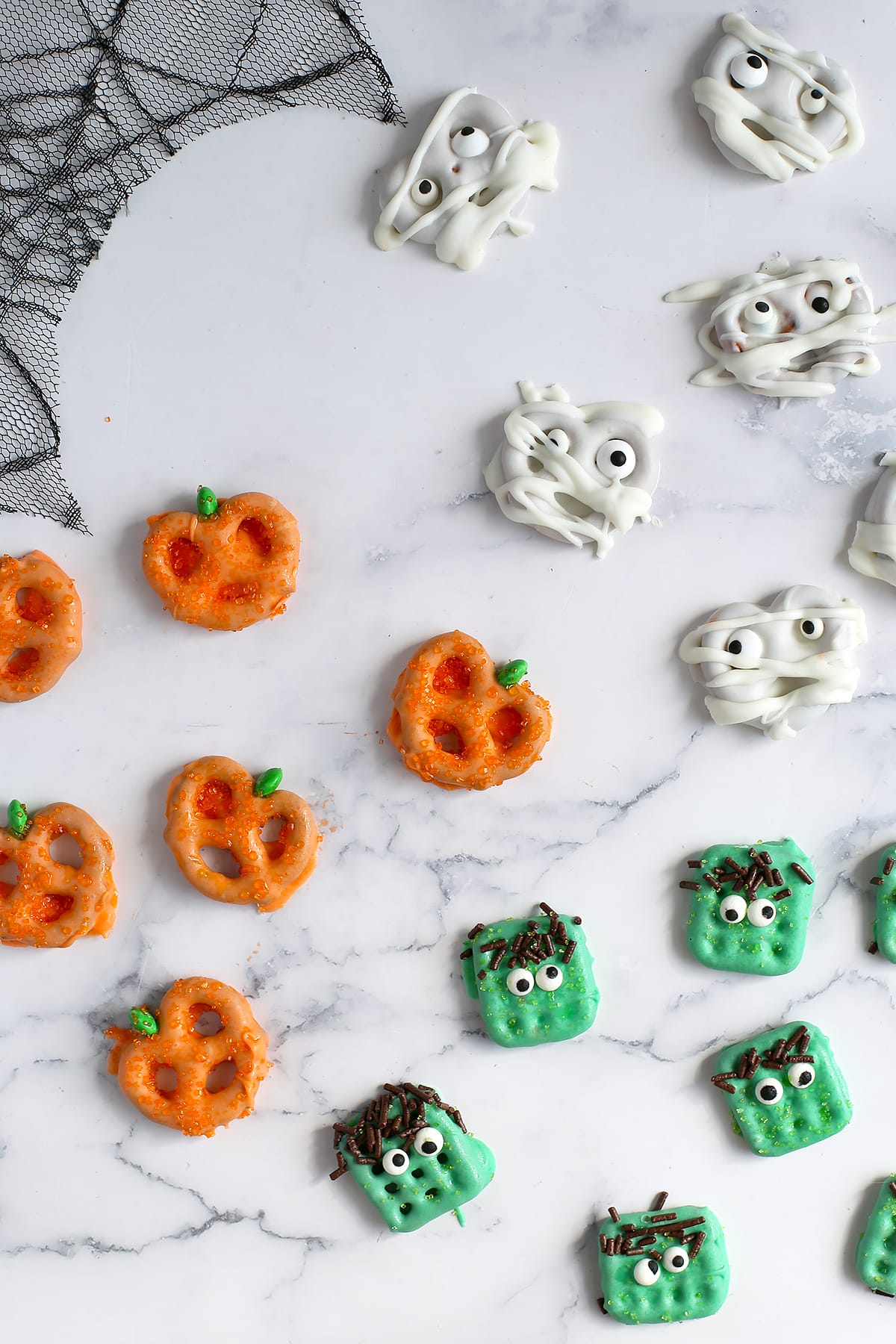 Halloween chocolate covered pretzels decorated like mummies, pumpkins, and frankensteins.