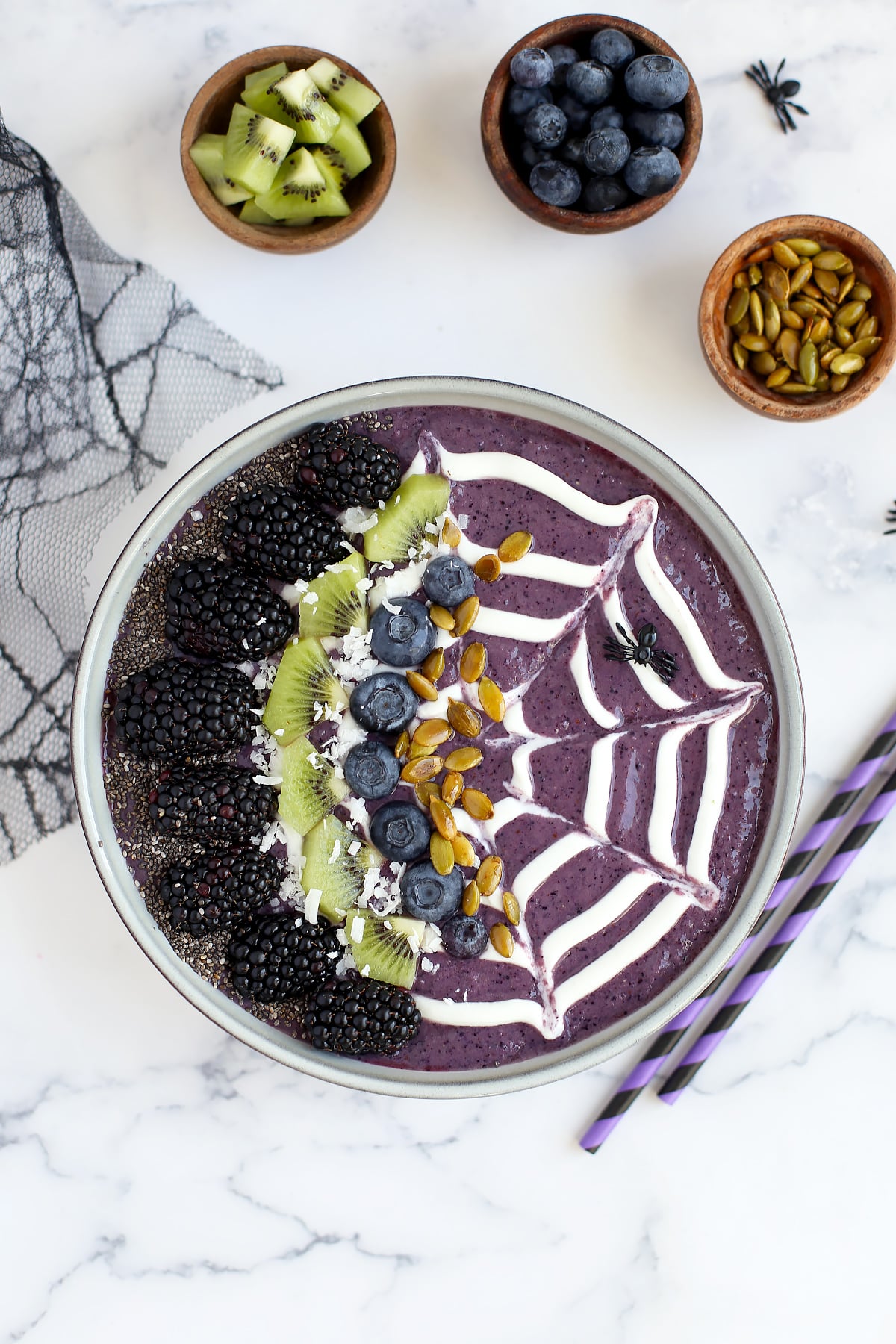 A bowl filled with a blueberry smoothie and topped with a ،y design and fresh fruit.