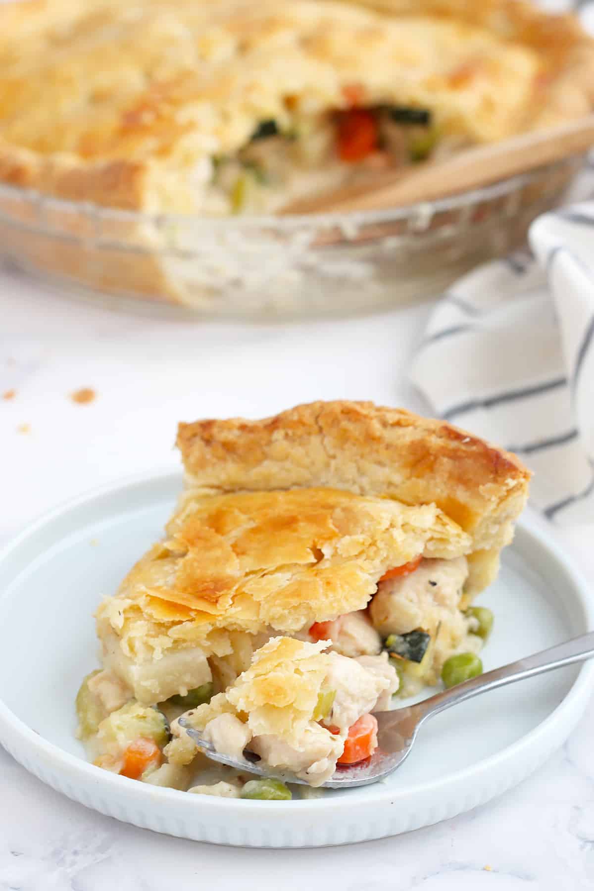 A slice of chicken pot pie with a flaky crust on a small serving plate.