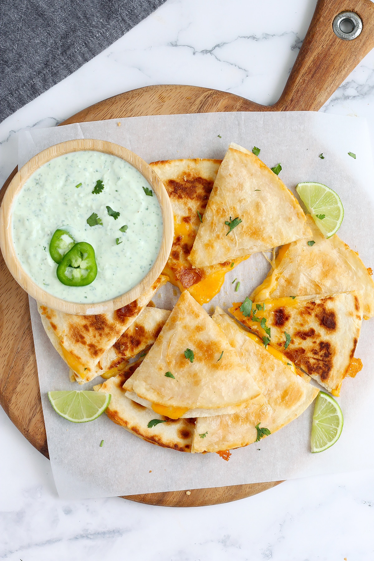 Cheese quesadillas served with a bowl of cilantro lime dressing and topped with sliced jalapenos.