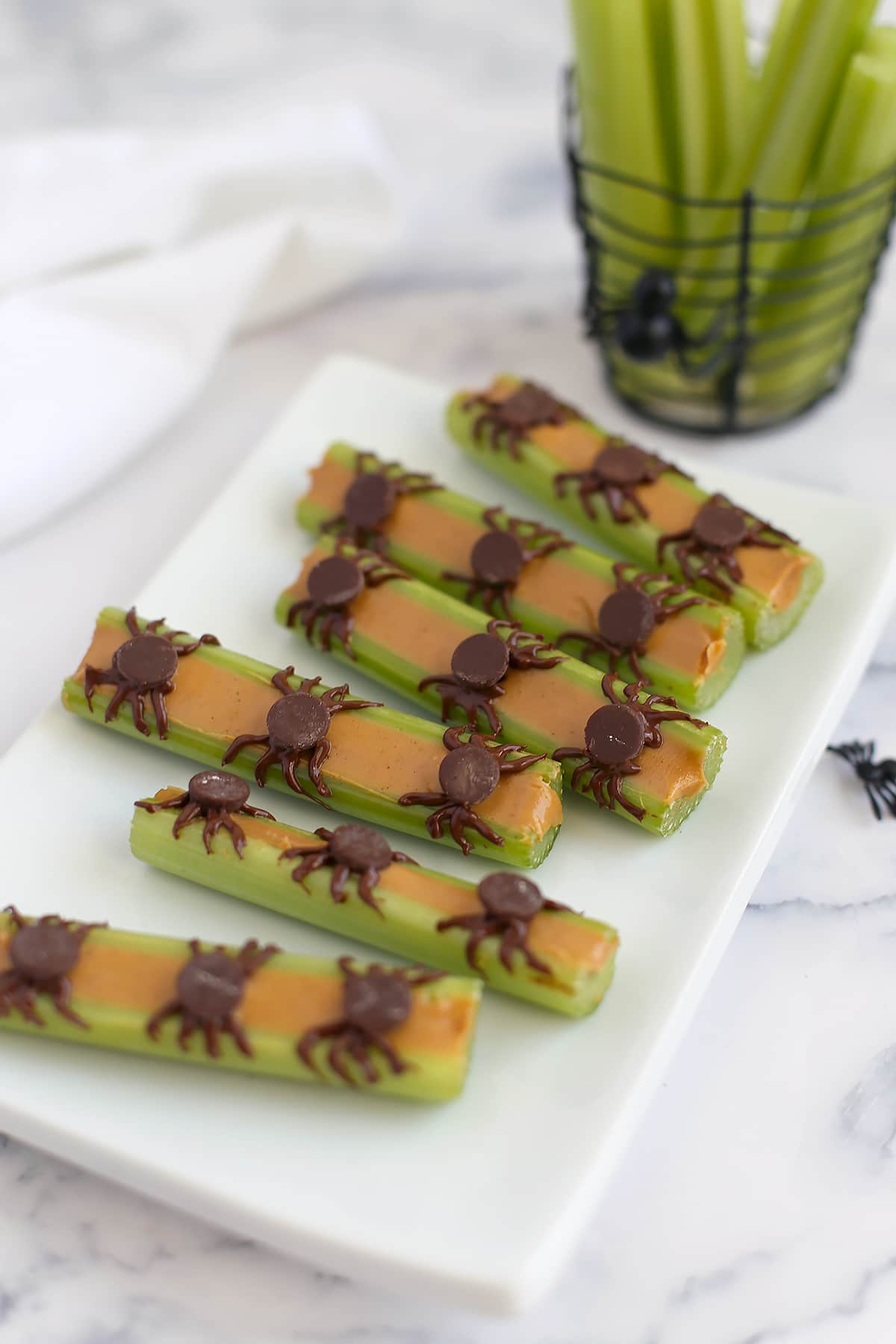 Spiders on a log halloween snack on a square white plate.