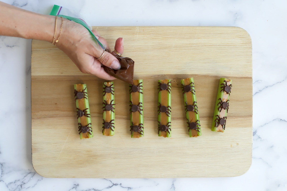 How to pipe chocolate legs onto Spiders on a Log snack.