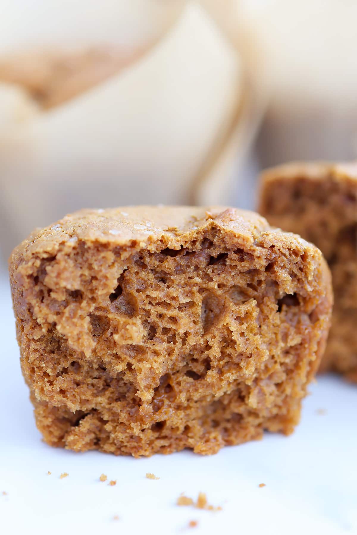 A spiced gingerbread muffin broken in half on a marble countertop.