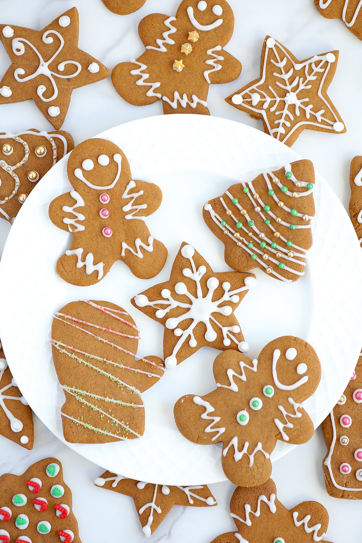 Soft gingerbread cutout cookies decorated with white icing and sprinkles on a serving plate.