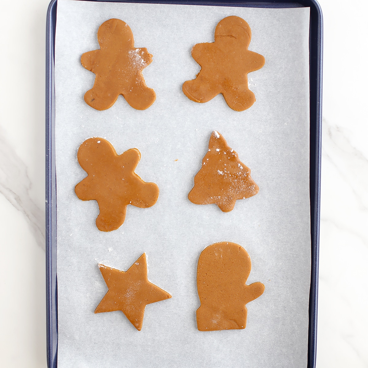 Gingerbread cookie dough on a parchment lined baking sheet.