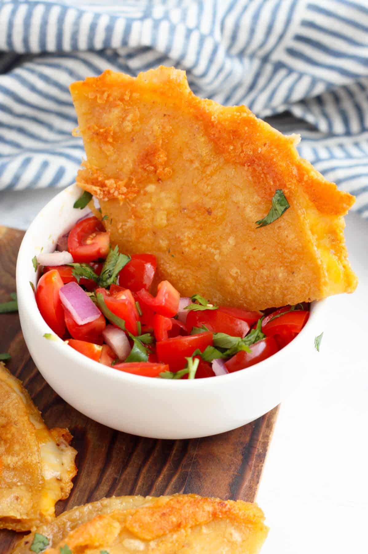 A quesadilla wedge stuck in a bowl of fresh pico de gallo