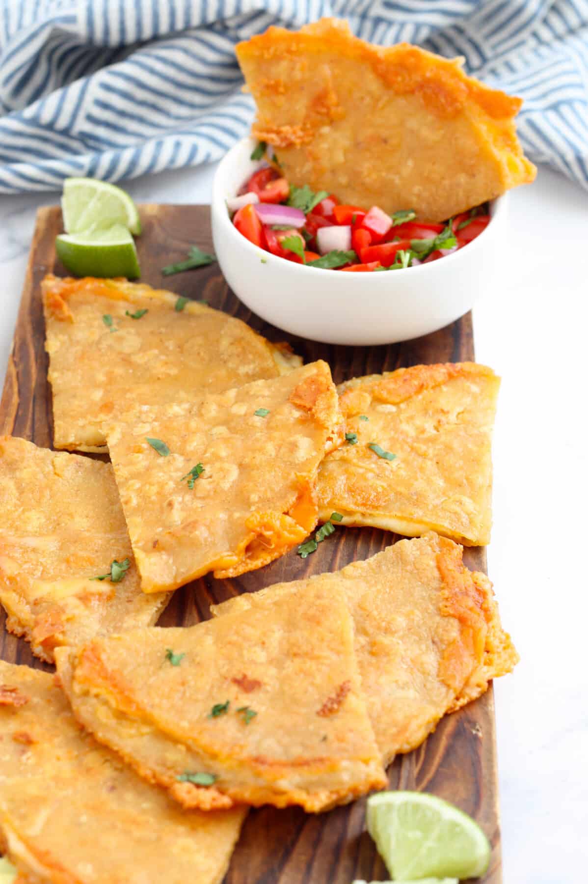 corn tortilla quesadilla wedges on a wooden serving board with fresh lime