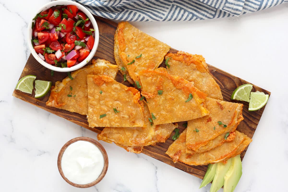 homemade corn tortilla quesadillas cut into wedges with fresh pico on a wooden board