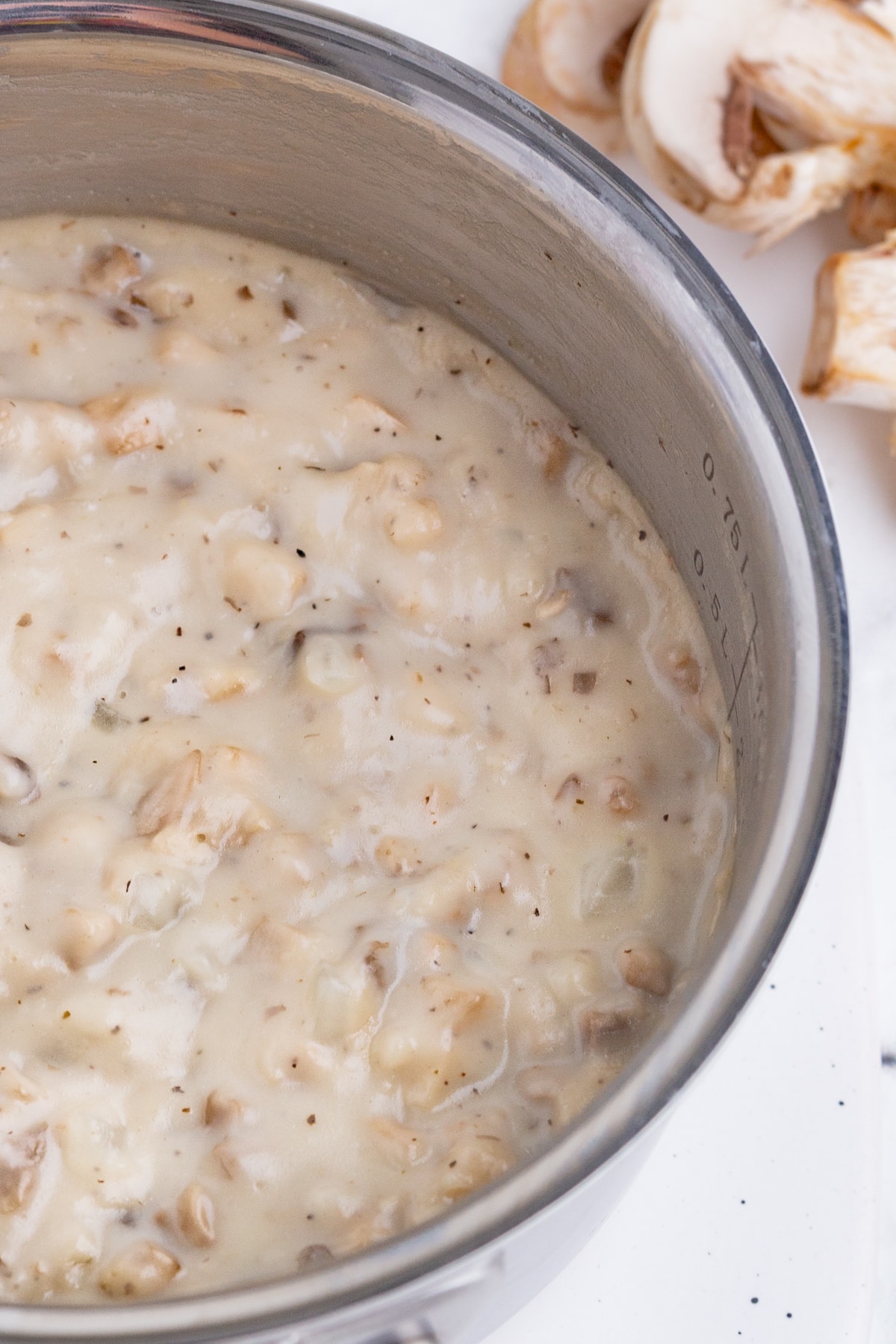 homemade cream of mushroom soup in a pot with fresh mushrooms in the background