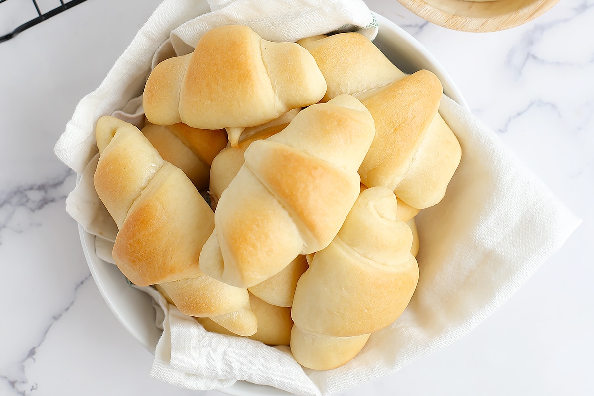 easy crescent rolls piled into a serving bowl with a white linen
