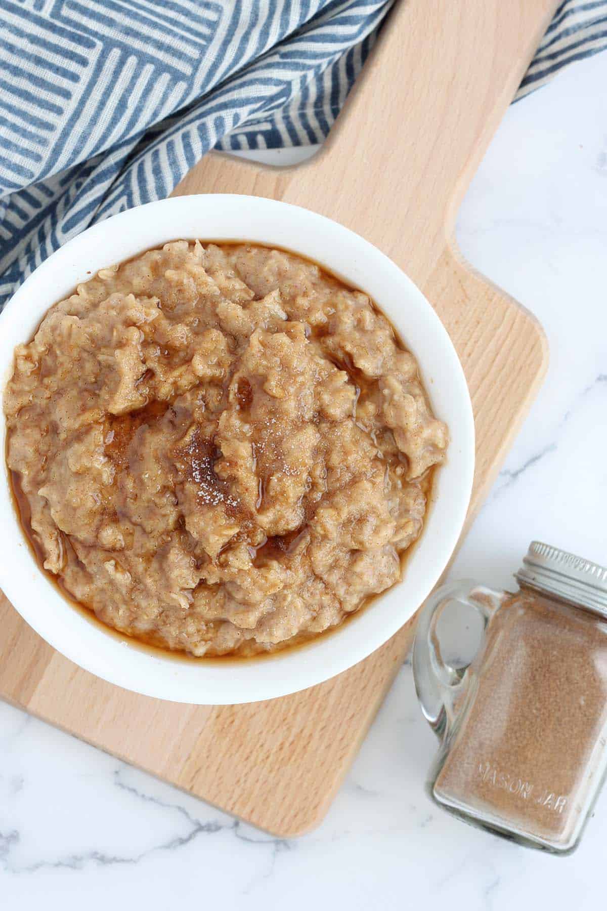 snickerdoodle oatmeal topped with cinnamon sugar on a small wooden serving board