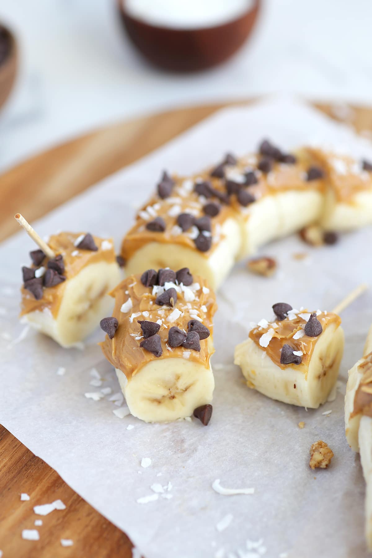 banana sushi snack with peanut butter, chocolate chips and coconut cut into slices and served with a toothpick