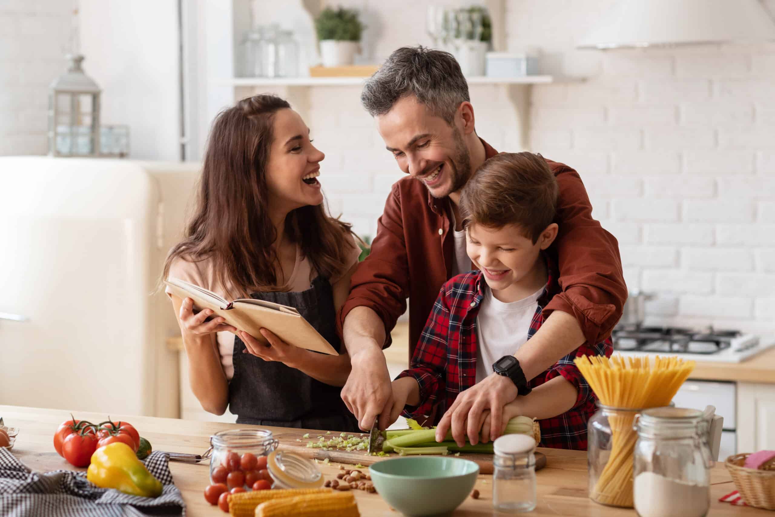 Family of husband, wife, and child happily cooking in the kitchen together.