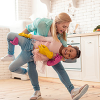 Mom and daughter having fun while cleaning home