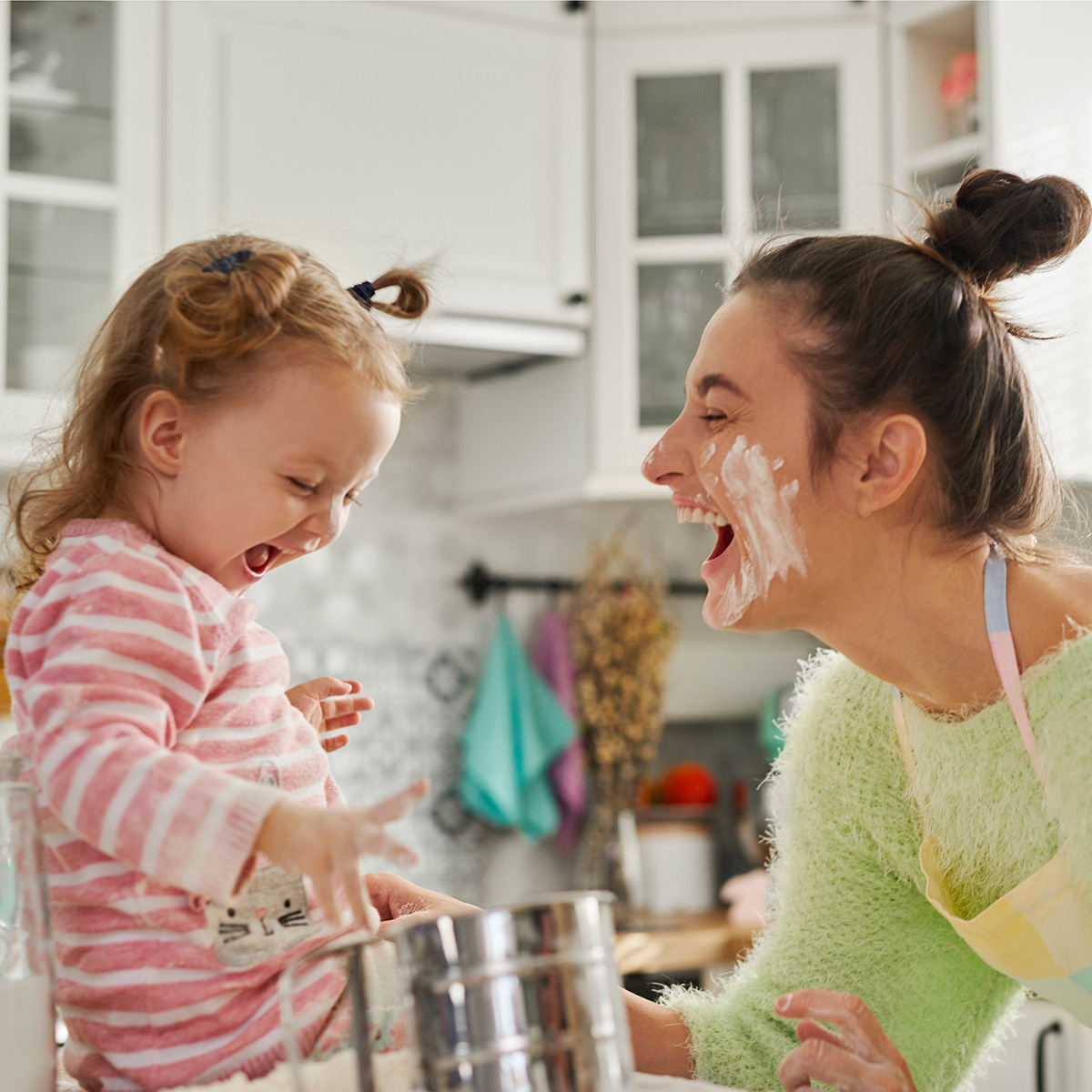 Mom and daughter covered in flour and having fun in the kitchen