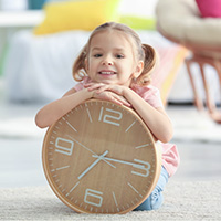 Girl sitting on the floor and leaning on a clock
