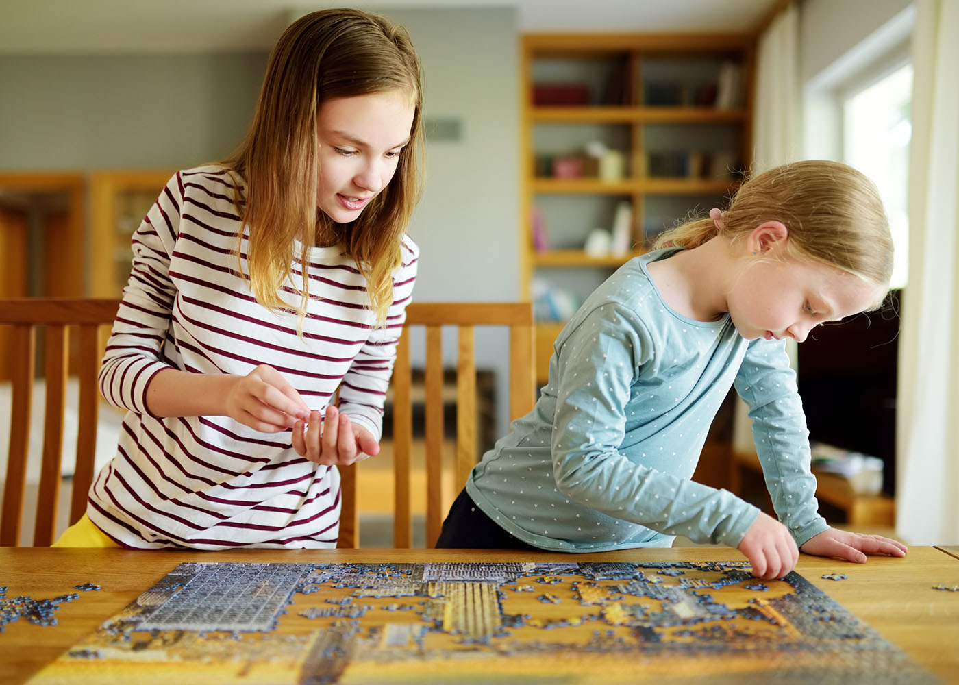 Two young girls putting together a puzzle on the kitchen table