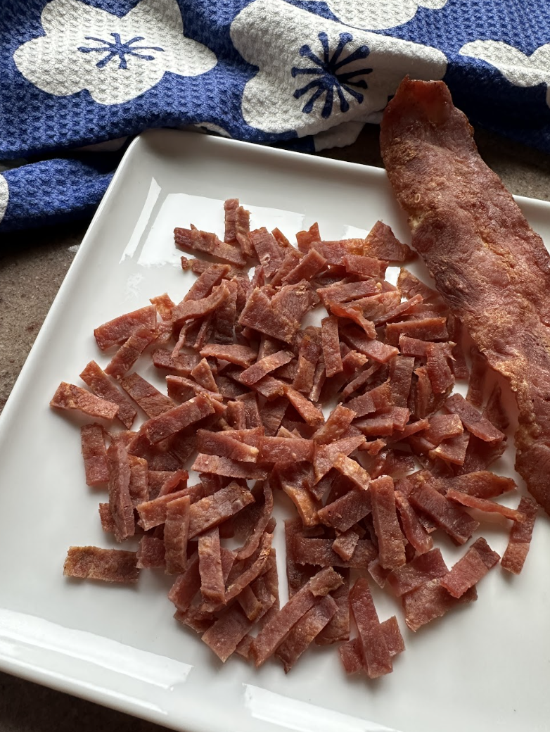 Crispy turkey bacon diced into pieces with a colorful linen in the background.