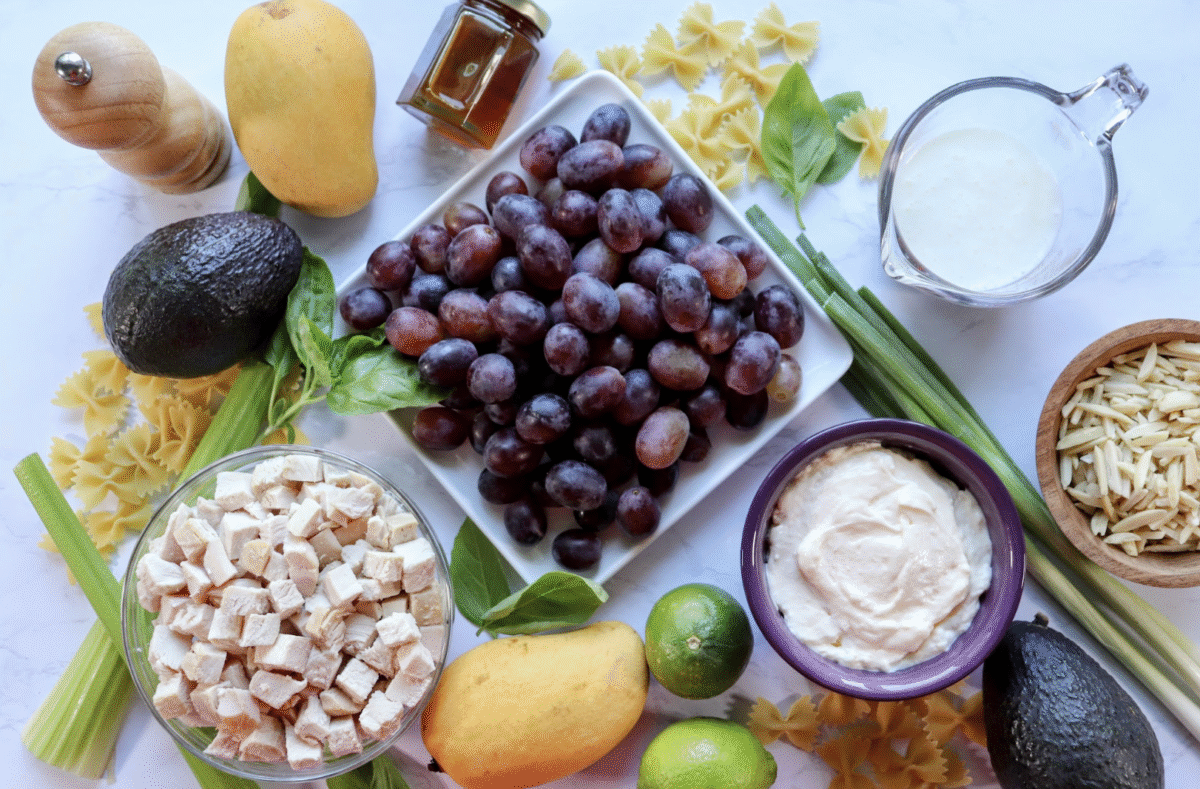 Make the mango chicken pasta salad spread the ingredients needed on the white marble countertop.